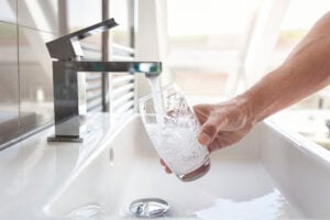 A glass being filled with water from a bathroom faucet.