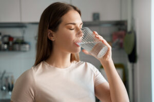 A young woman drinking fresh water from a glass.
