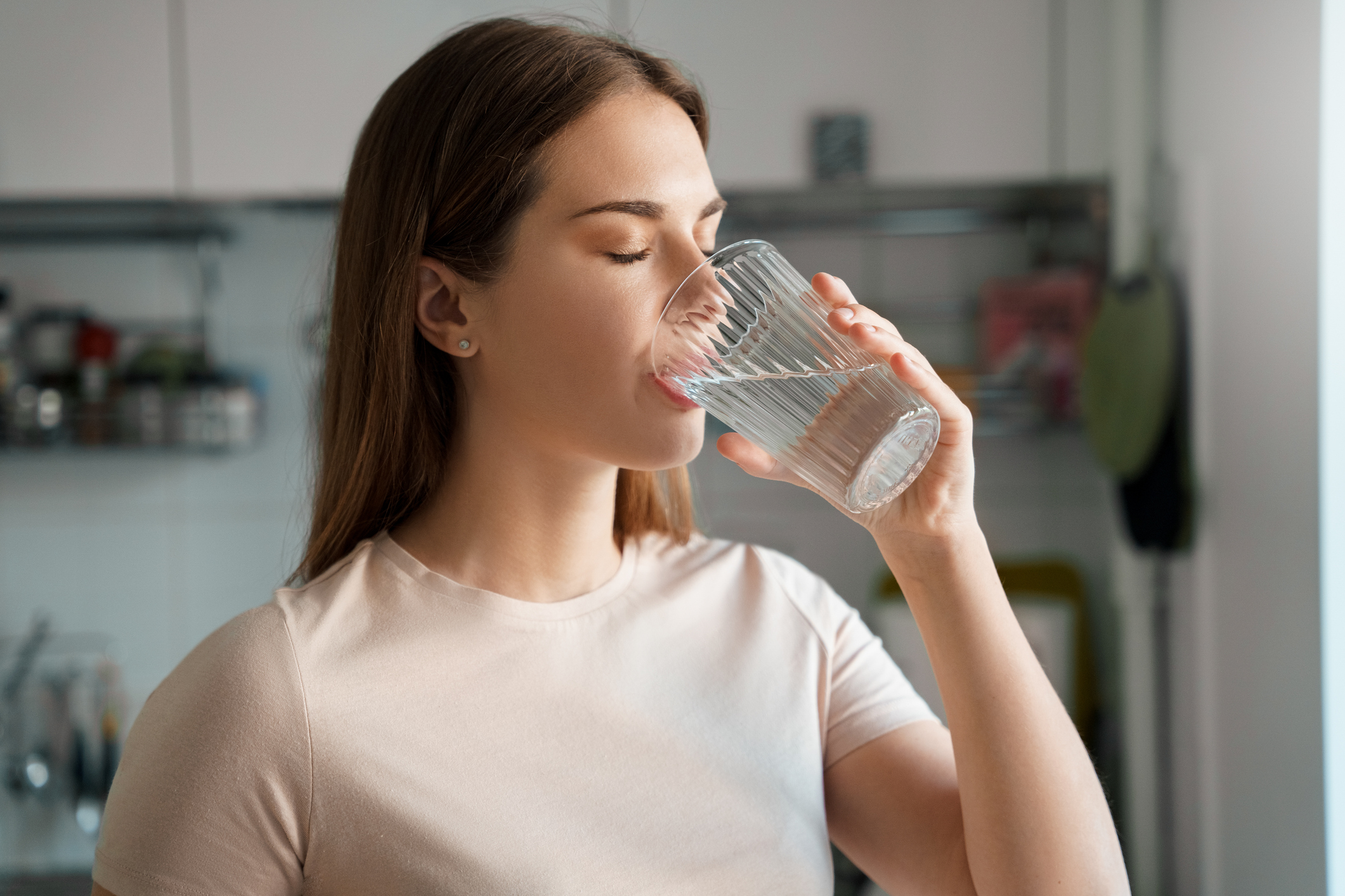 A young woman drinking fresh water from a glass.