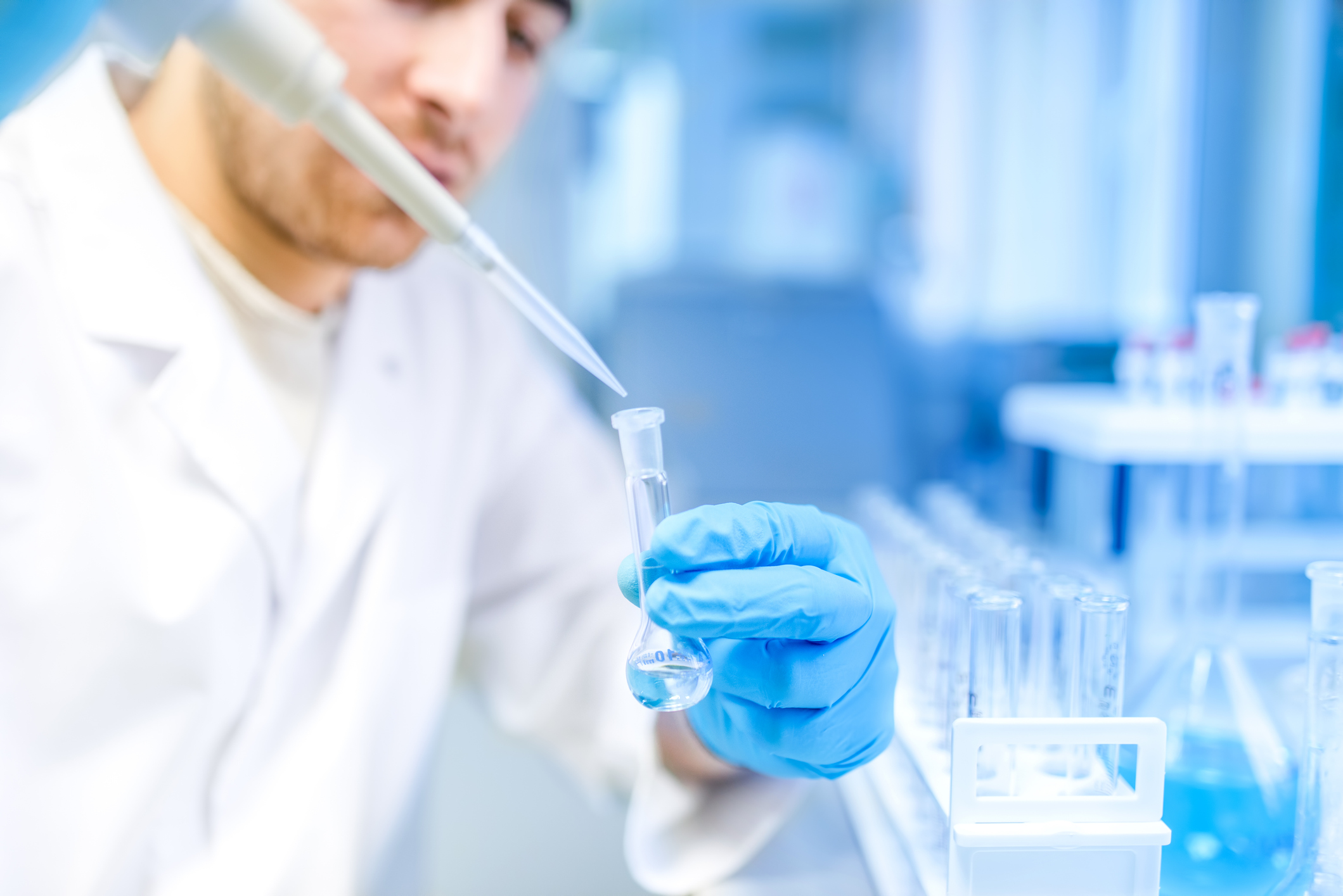 A scientist using a pipette to extract liquid in a laboratory.