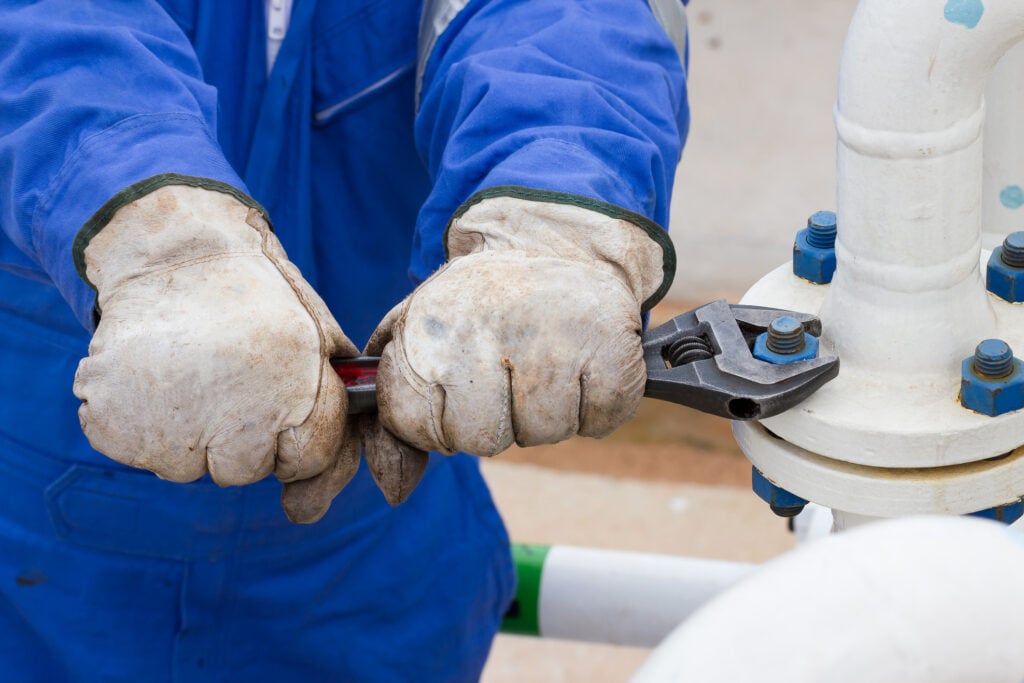 A person using a wrench to stop a water leak.