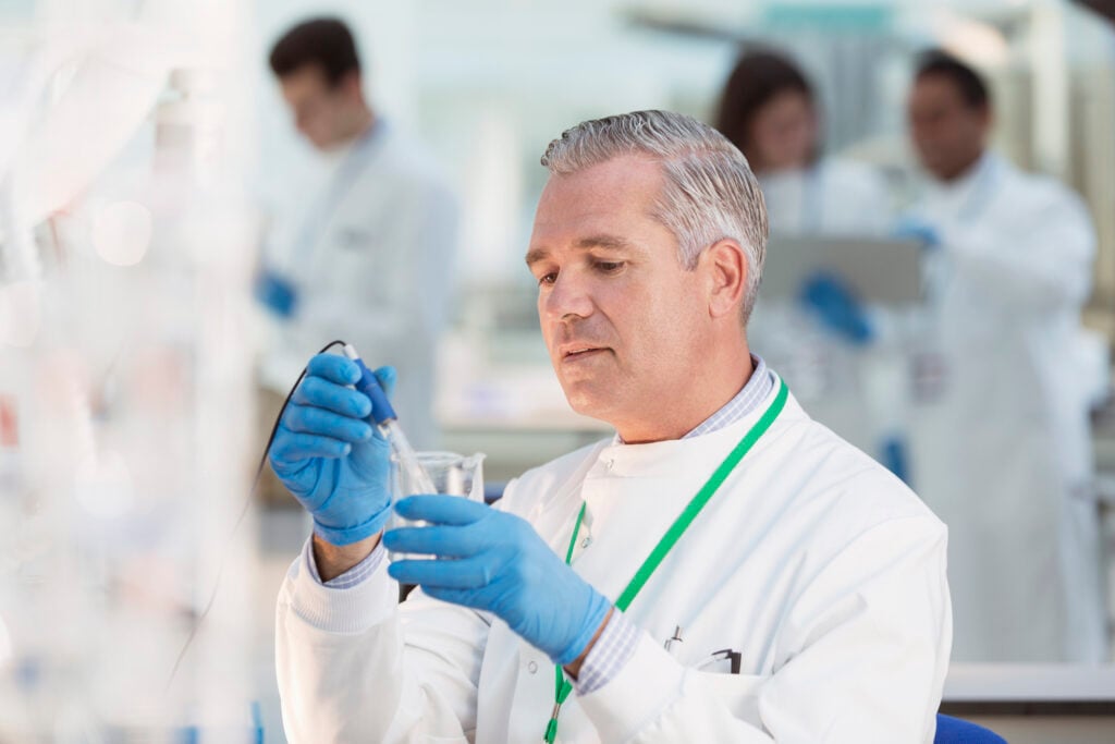 A scientist examining a beaker with a water sample.