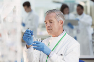 A scientist examining a beaker with a water sample.
