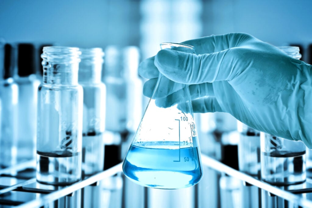 Scientist holding a water sample for bacterial testing in a laboratory